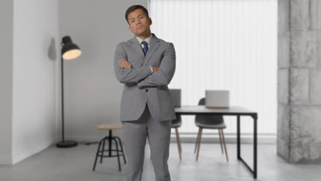Portrait-Of-Serious-Businessman-Wearing-Suit-Standing-In-Modern-Open-Plan-Office